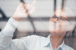 © Westend61 - Businesswoman touching glass window at work place