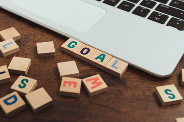 The word GOAL made of wooden blocks with alphabet letters working table background closeup selective focus achievement concept . High quality photo