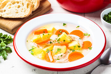 Wall Mural - Traditional chicken soup with vegetables in white plate, gray background. Home cooking concept.