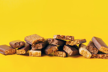 Wall Mural - Whey protein powder in measuring scoop and different energy protein bar on yellow background.