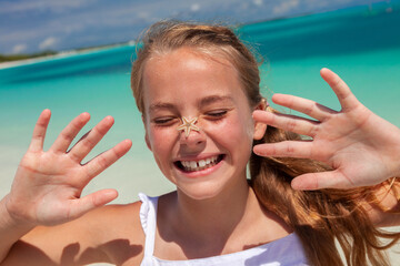 Wall Mural - Portrait of female youth playing with beach starfish