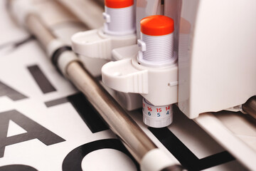 Leinwandbilder - tool head of cutting plotter with two adjustable cutting blades while making adhesive lettering from black vinyl foil in bright light. technical close up view. selective focus. advertising concept
