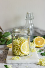 Wall Mural - Homemade elderflower syrup with lemons and freshly picked elderflowers. The flowers are edible and can be used to add flavour and aroma to both drinks and desserts.