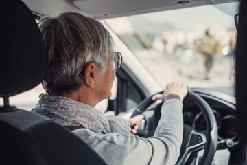 Happy owner. Handsome mature woman sitting relaxed in his newly bought car looking at the road smiling joyfully. One old senior driving and having fun..