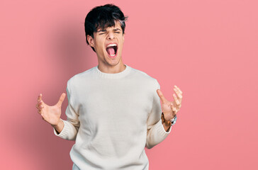 Canvas Print - Handsome hipster young man wearing casual winter sweater crazy and mad shouting and yelling with aggressive expression and arms raised. frustration concept.