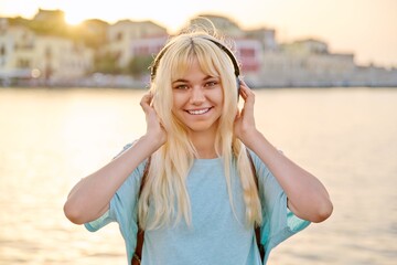 Poster - Outdoor portrait of happy young blonde woman wearing headphones