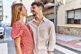 Fototapeta Miasto - Young hispanic couple smiling happy and hugging standing at the city.