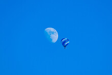 Blue Hot Air Balloon Floating On Blue Sky Near Gibbous Moon