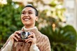 © Krakenimages.com - Beautiful hispanic woman with short hair smiling happy outdoors holding vintage camera