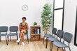 © Krakenimages.com - Young hispanic woman reading book sitting on chair at waiting room