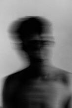 Grayscale blurry portrait of topless man against light background