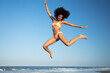 Fun loving Afro female jumping by the ocean