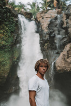 Portrait Of Young Man Standing In Front Of Waterfall
