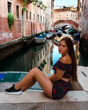 Side View Of Young Woman In Floral Crop Top Sitting On Floor In Venice, Italy