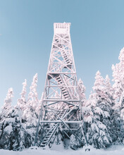 Snow Covered Metal Tower In The Woods Under Blue Sky