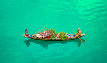 Top View Of Mother And Daughter Sitting On A Boat Selling Fresh Produce In Bangladesh