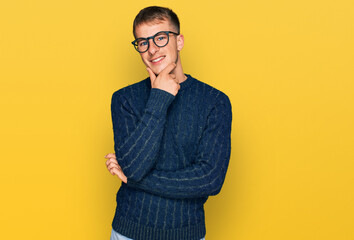 Poster - Young blond man wearing casual clothes and glasses looking confident at the camera smiling with crossed arms and hand raised on chin. thinking positive.