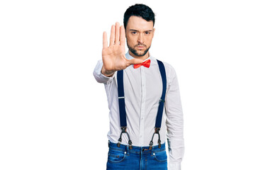 Poster - Hispanic man with beard wearing hipster look with bow tie and suspenders doing stop sing with palm of the hand. warning expression with negative and serious gesture on the face.