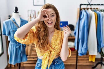 Canvas Print - Young caucasian woman at retail shop holding credit card smiling happy doing ok sign with hand on eye looking through fingers