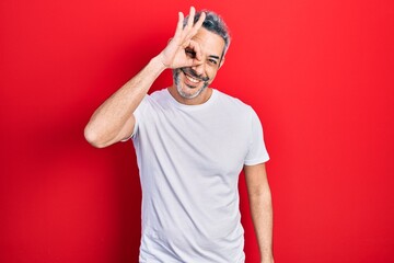 Sticker - Handsome middle age man with grey hair wearing casual white t shirt smiling happy doing ok sign with hand on eye looking through fingers