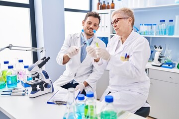 Sticker - Mother and son scientist partners holding test tubes writing on clipboard at laboratory