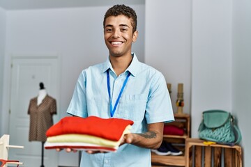 Wall Mural - Young hispanic man working as shop assistant at retail shop