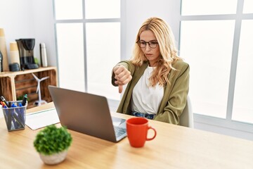 Sticker - Beautiful blonde woman working at the office with laptop looking unhappy and angry showing rejection and negative with thumbs down gesture. bad expression.