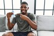 © Krakenimages.com - Young african american man holding blue ribbon sitting on the sofa at home smiling happy pointing with hand and finger