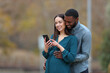 © PheelingsMedia - Pregnant wife and her husband checking smart phone