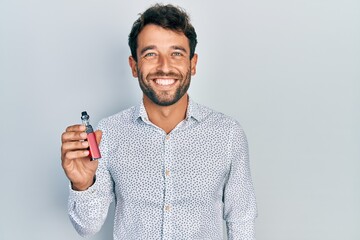 Sticker - Handsome man with beard football reporter holding electronic cigarette looking positive and happy standing and smiling with a confident smile showing teeth