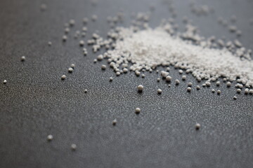 Small round granules on a black background. Laundry bleaching powder in granules.