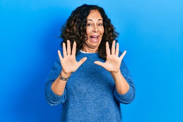 Canvas Print - Middle age hispanic woman wearing casual clothes afraid and terrified with fear expression stop gesture with hands, shouting in shock. panic concept.