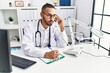 © Krakenimages.com - Young hispanic man wearing doctor uniform speaking on the phone at clinic