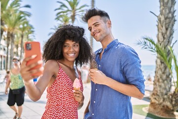 Wall Mural - Man and woman couple eating ice cream make selfie by the smartphone at seaside