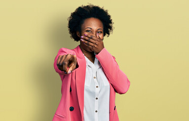 Sticker - African american woman with afro hair wearing business jacket laughing at you, pointing finger to the camera with hand over mouth, shame expression