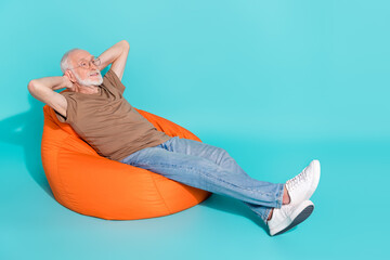 Sticker - Full length body size view of attractive cheery grey-haired man lying in bag chair resting isolated over bright blue color background