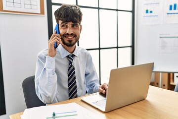 Wall Mural - Young hispanic businessman talking on the smartphone working at the office.