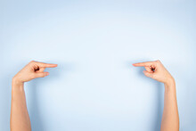 Woman Hands Pointing Index Finger To Each Other Towards The Center. Female Hands Show Something Virtual And Invisible Isolated On Light Blue Background
