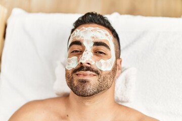 Canvas Print - Young hispanic man having facial mask treatment at beauty center