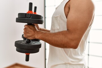 Sticker - Young hispanic man training using dumbbells at sport center