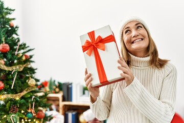 Poster - Middle age caucasian woman smiling confident holding christmas gift at home