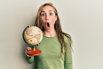 Canvas Print - Young blonde woman holding vintage world ball scared and amazed with open mouth for surprise, disbelief face