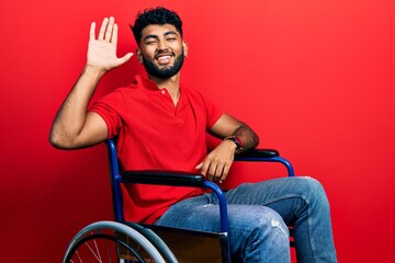 Sticker - Arab man with beard sitting on wheelchair waiving saying hello happy and smiling, friendly welcome gesture