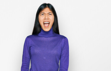 Sticker - Beautiful young asian woman wearing casual clothes angry and mad screaming frustrated and furious, shouting with anger. rage and aggressive concept.