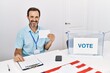 © Krakenimages.com - Middle age man with beard voting putting envelop in ballot box looking positive and happy standing and smiling with a confident smile showing teeth