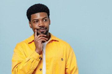 Wall Mural - Young minded pensive thoughtful man of African American ethnicity 20s wear yellow shirt look aside prop up chin think isolated on plain pastel light blue background studio. People lifestyle concept.