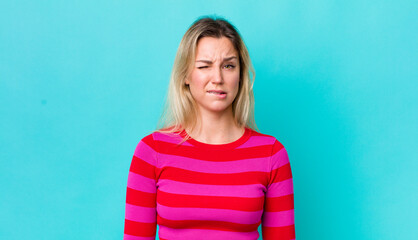 Wall Mural - pretty blonde woman feeling clueless, confused and uncertain about which option to pick, trying to solve the problem