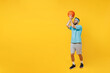 © ViDi Studio - Full size fun young fitness trainer instructor sporty man sportsman in headband blue t-shirt spend leisure time in gym throw basketball ball isolated on plain yellow background. Workout sport concept.