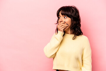 Wall Mural - Young hispanic woman isolated on pink background thoughtful looking to a copy space covering mouth with hand.