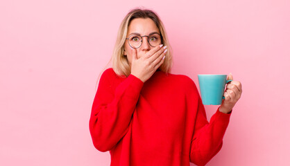 blonde pretty woman covering mouth with hands with a shocked. coffee cup concept